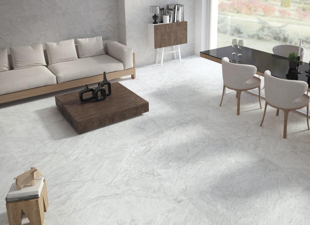 Modern living room with a beige sofa, wooden coffee table, dining table with chairs, and large window overlooking a garden.