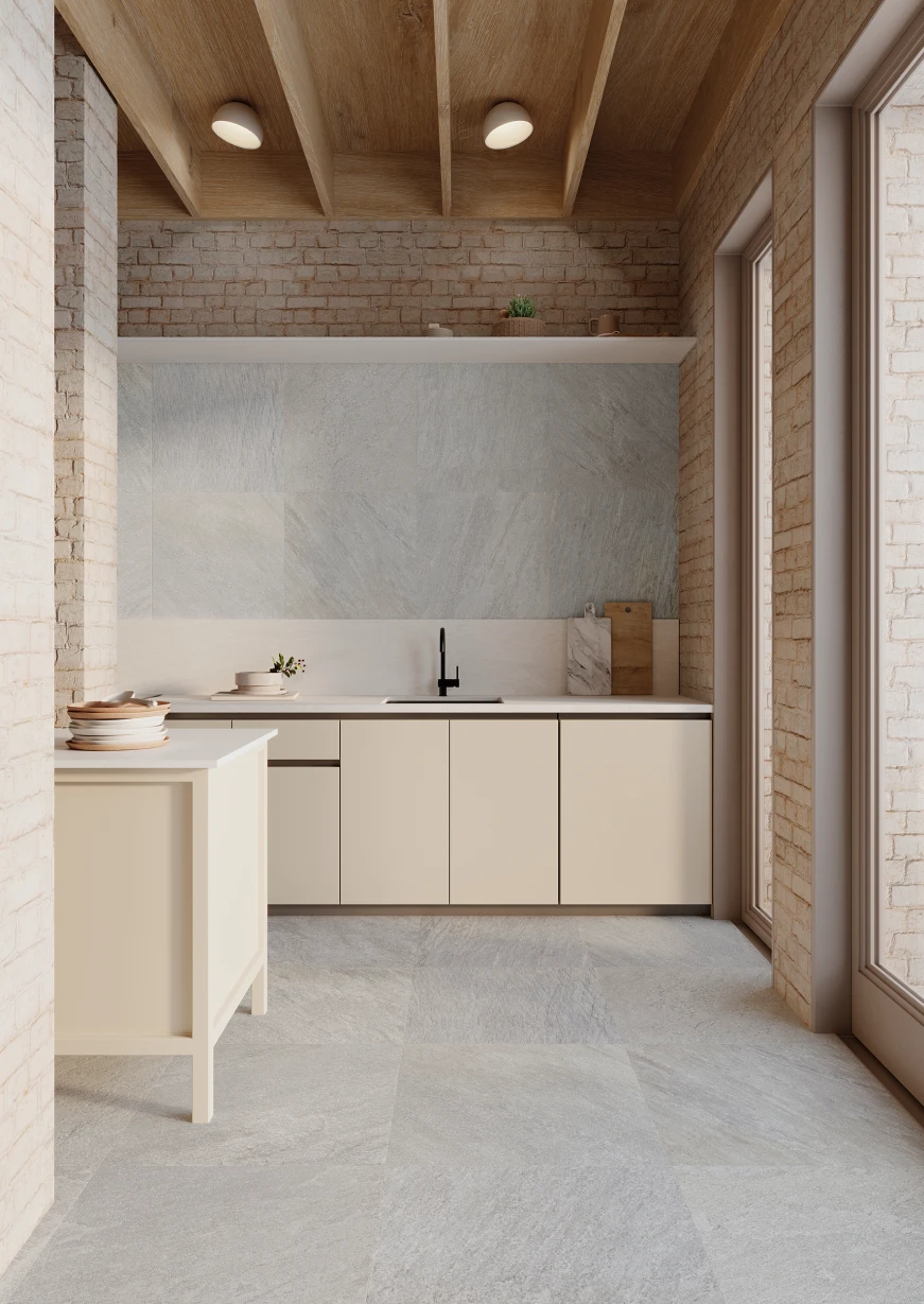 Modern kitchen with beige cabinets, light stone tile floor and backsplash, exposed brick walls, and wooden ceiling beams.