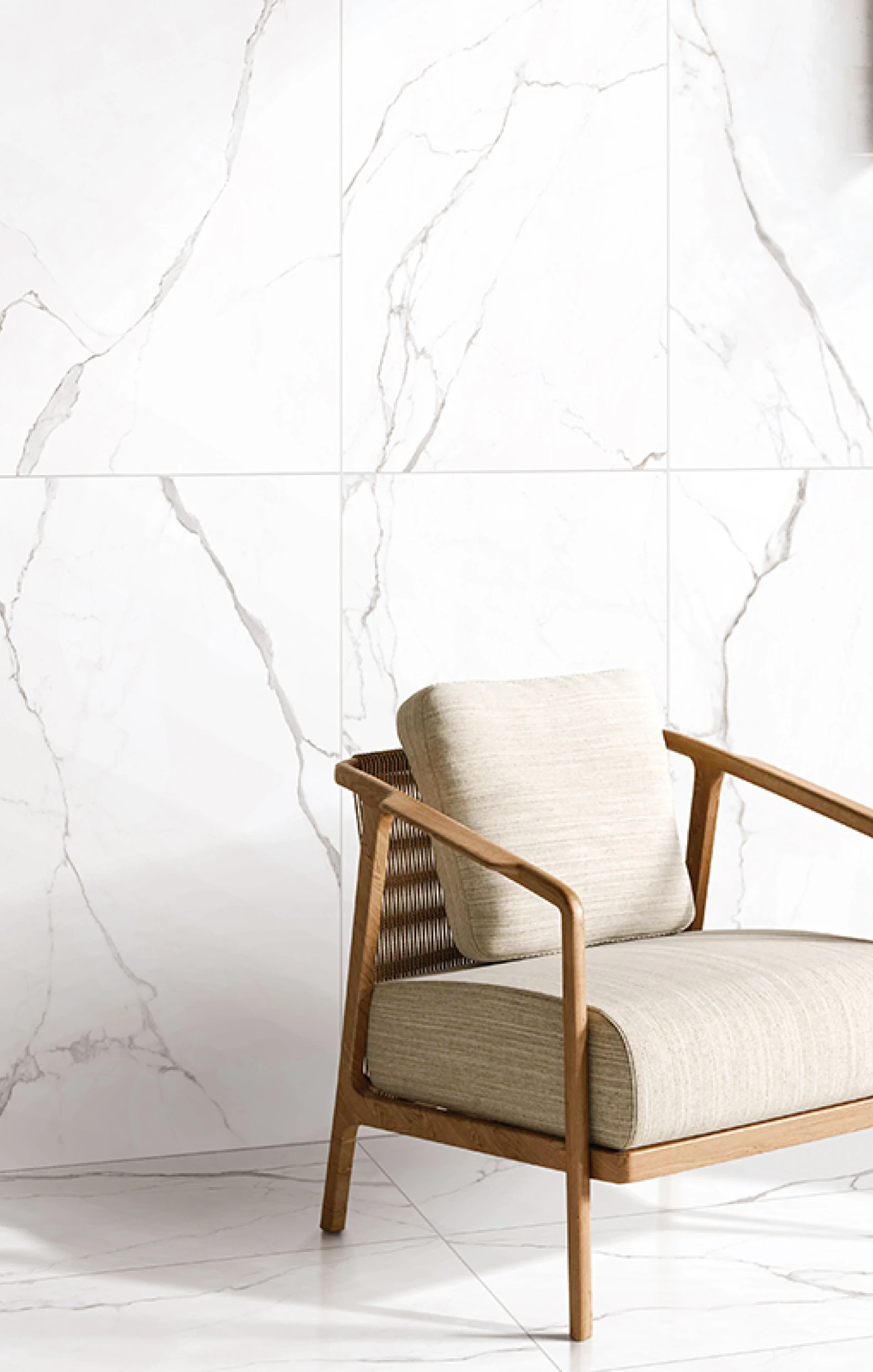 Light beige cushioned wooden armchair with woven backrest against white marble wall and floor.