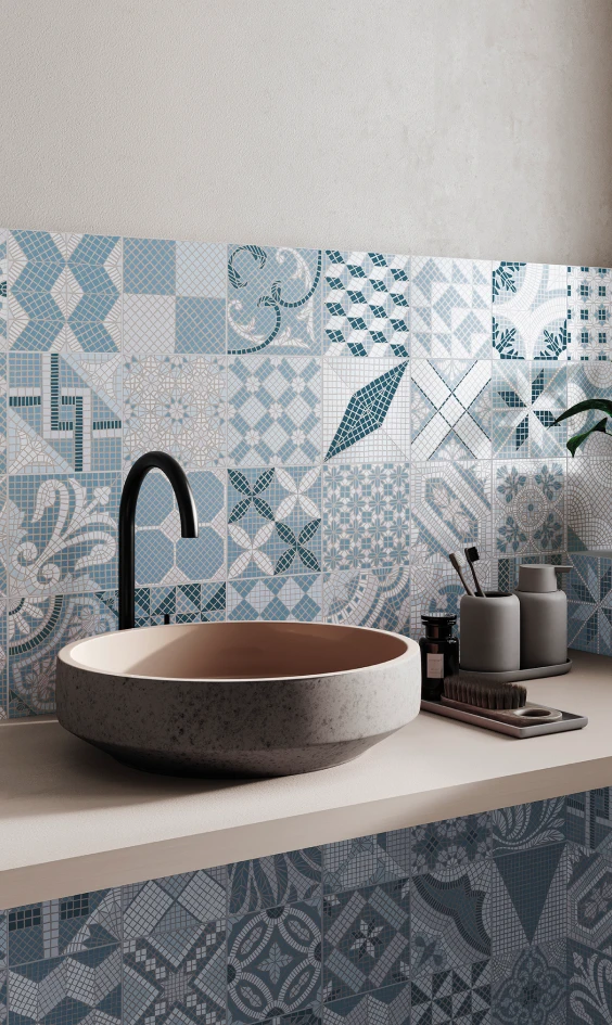 Modern bathroom sink with round stone basin, black faucet, and blue decorative patterned tiles on wall and counter backsplash.
