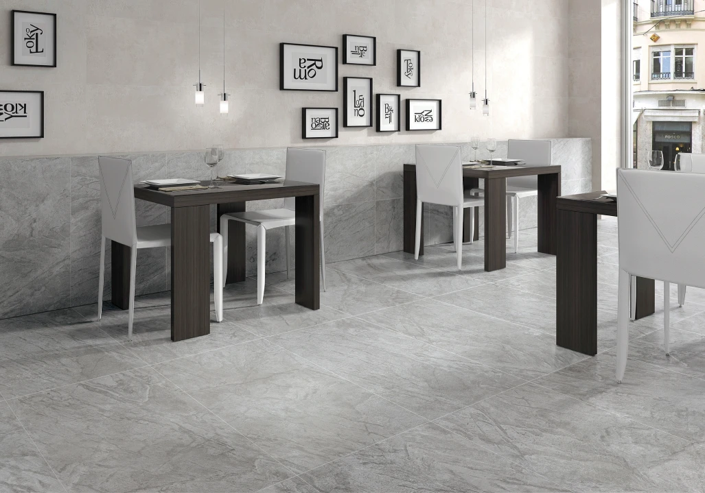 Modern cafe interior with gray marble floor and walls, dark wood tables, white chairs, and framed abstract art on the walls.