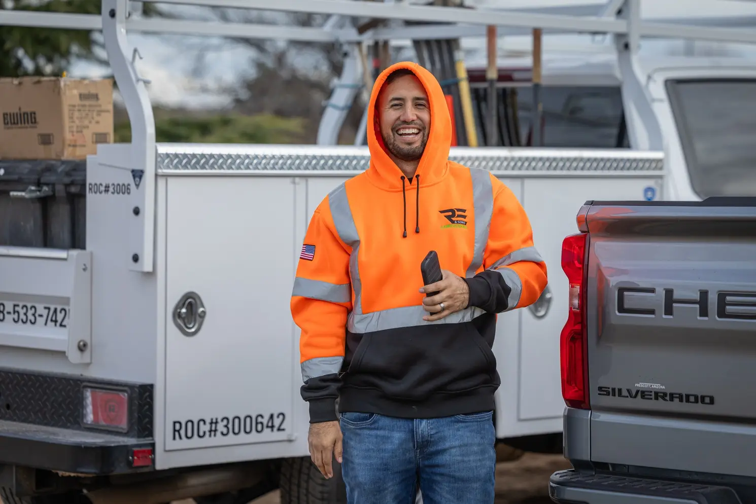An RE and Sons team member smiling by the work trucks