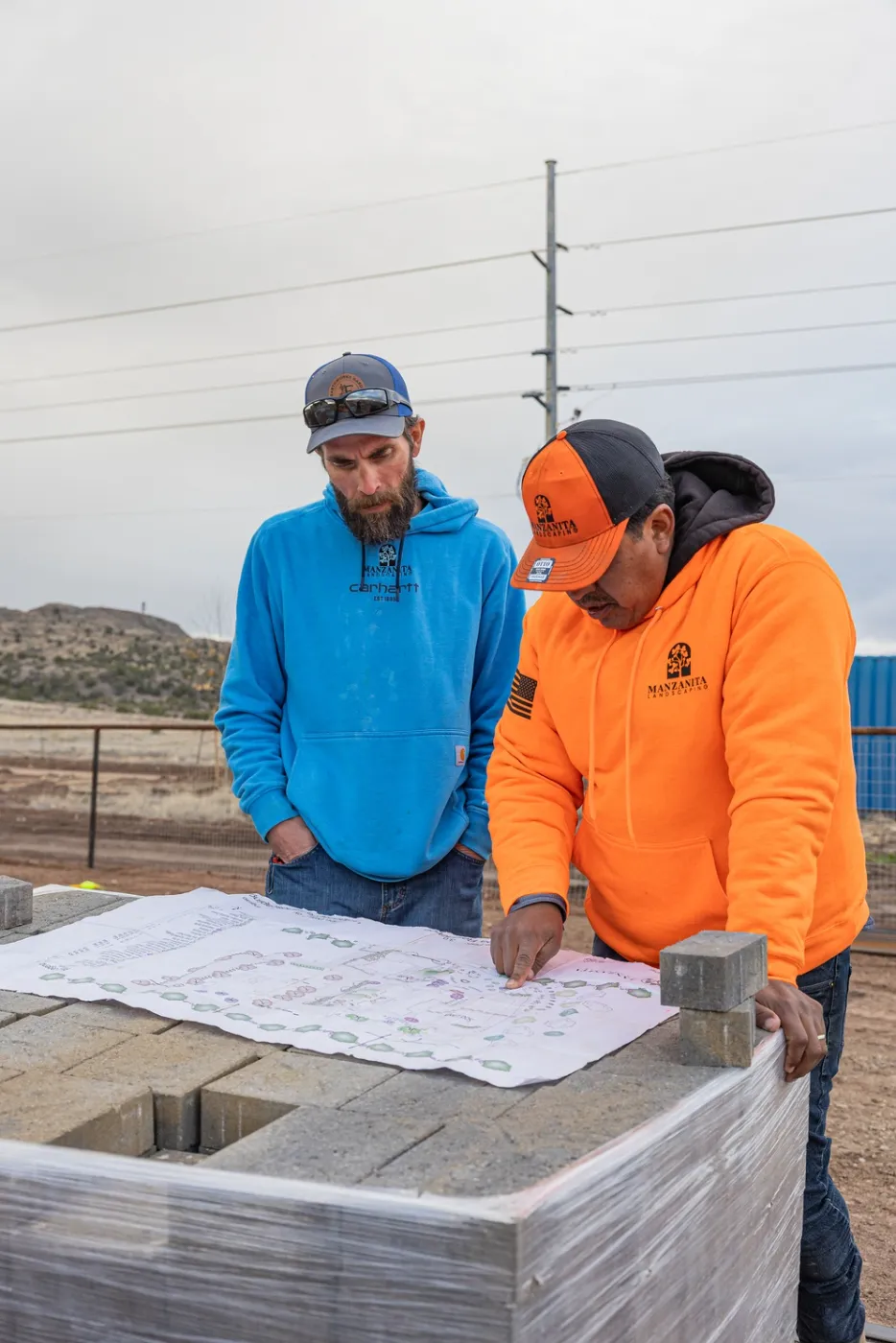 Two Manzanita crew leads reading a plan spread over a pallet of block