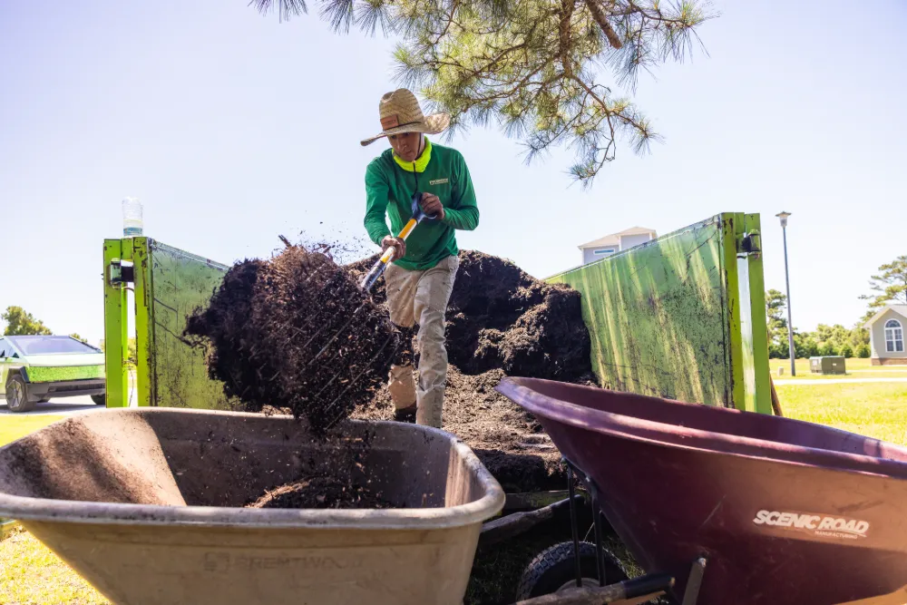 A ProGreen crew member shoveling mulch on a hot day