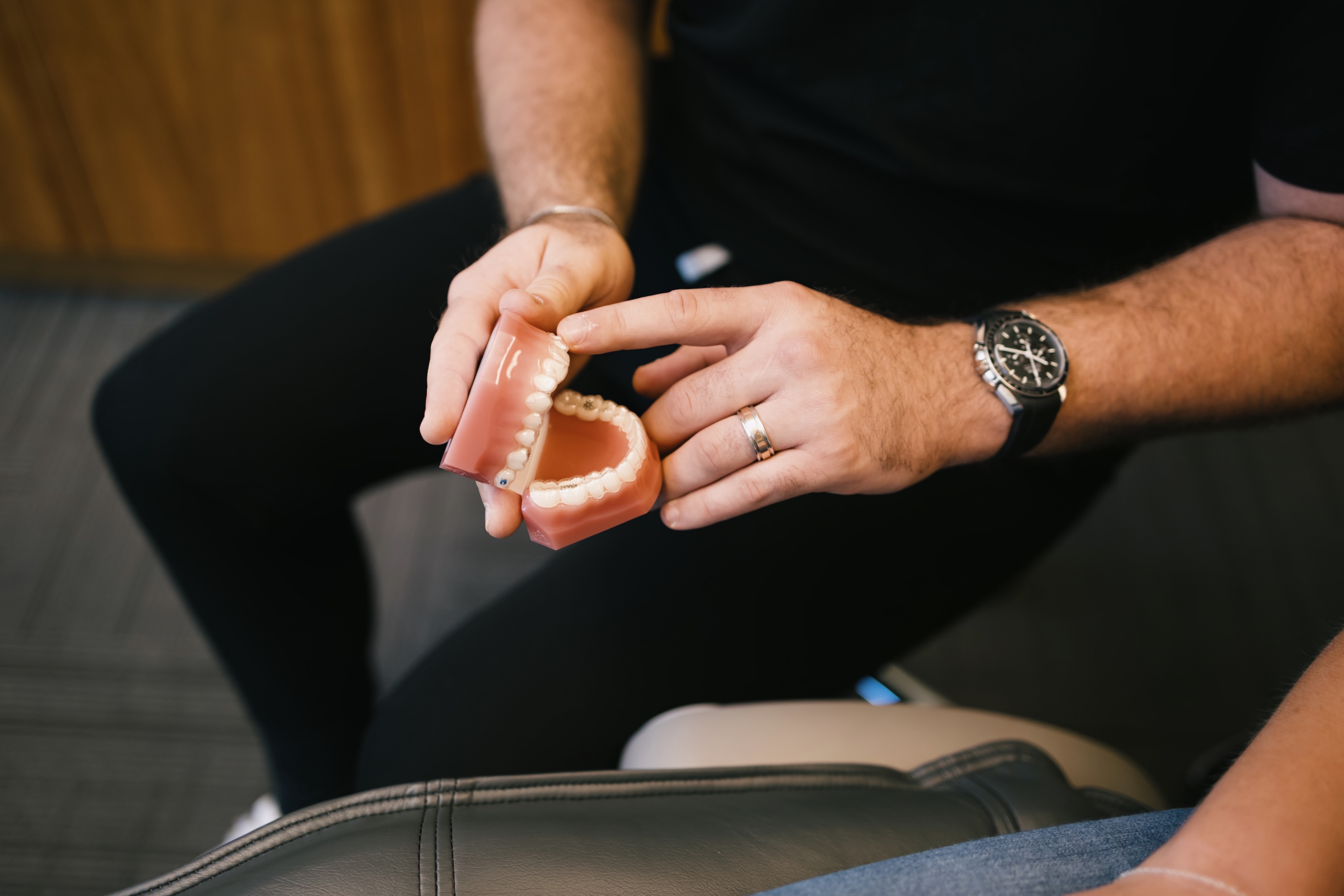 The dentist is holding a 3D model of a set of teeth and showing the patient where the dental implant would go.