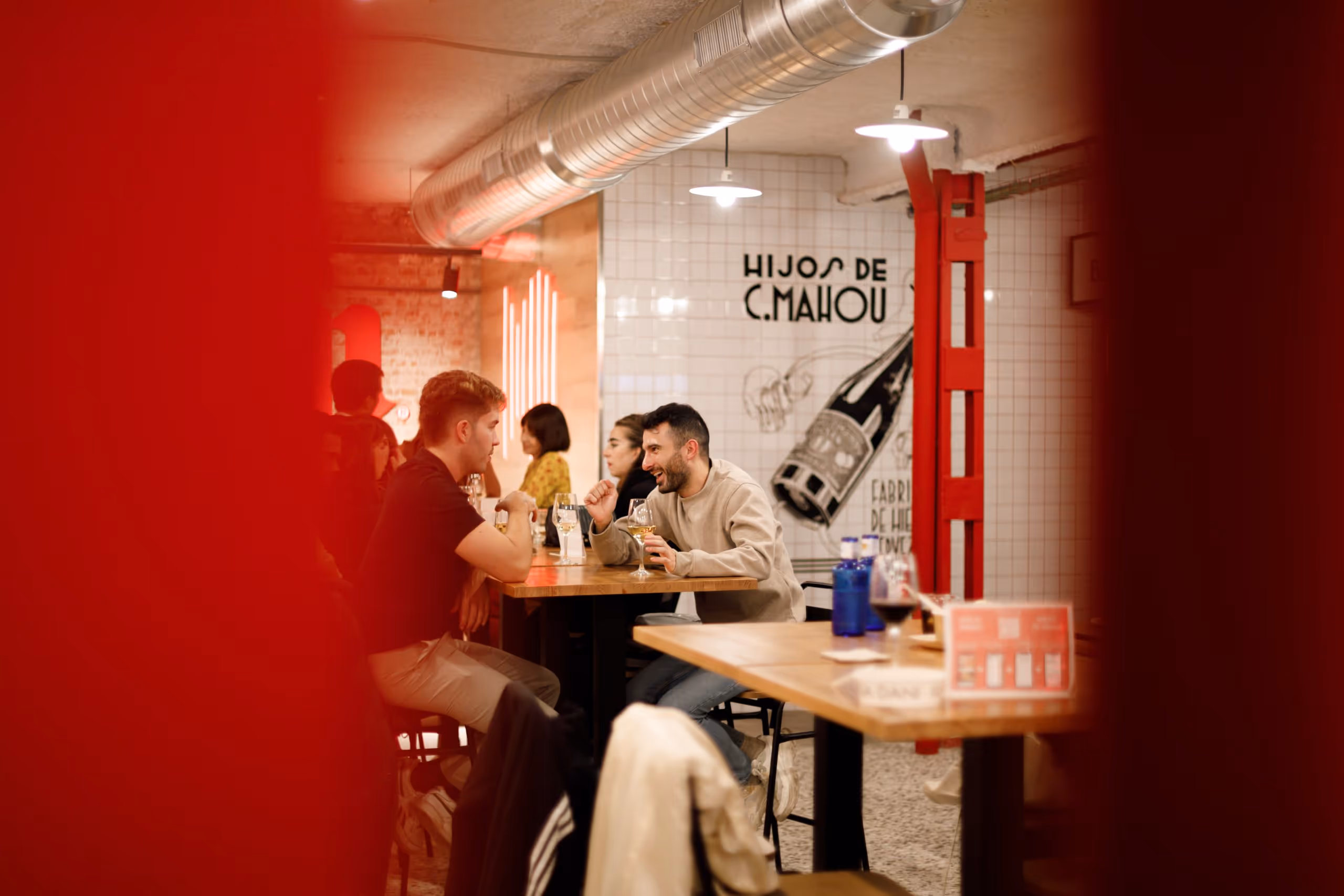 Dos hombres sentados en una mesa hablan y beben en el mercado San Leopoldo.
