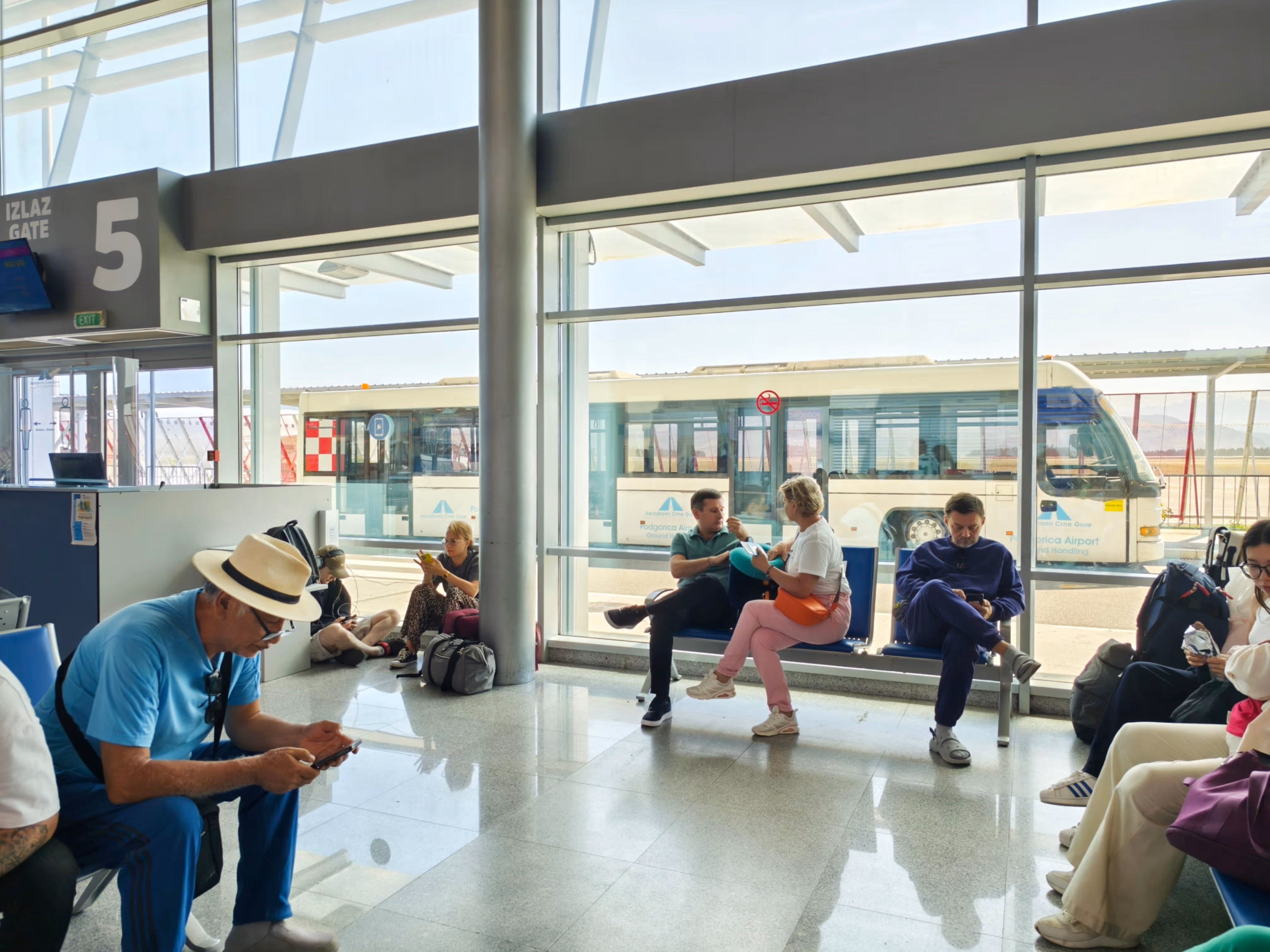 Passengers waiting at Gate 5 in Podgorica Airport departure lounge, Montenegro.