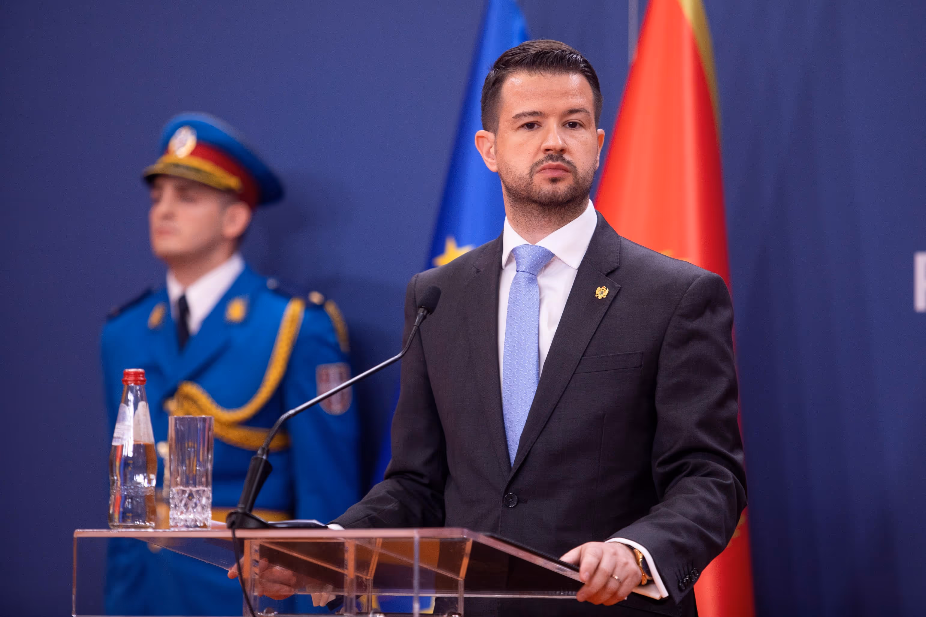 President Milatović of Montenegro speaking at a podium with EU and Montenegrin flags in the background