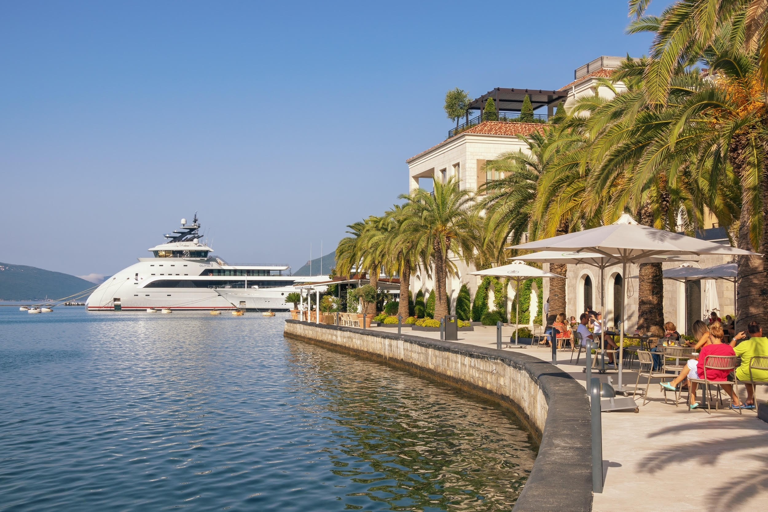 Porto Montenegro waterfront with superyacht, palm trees and mountains, Tivat Bay