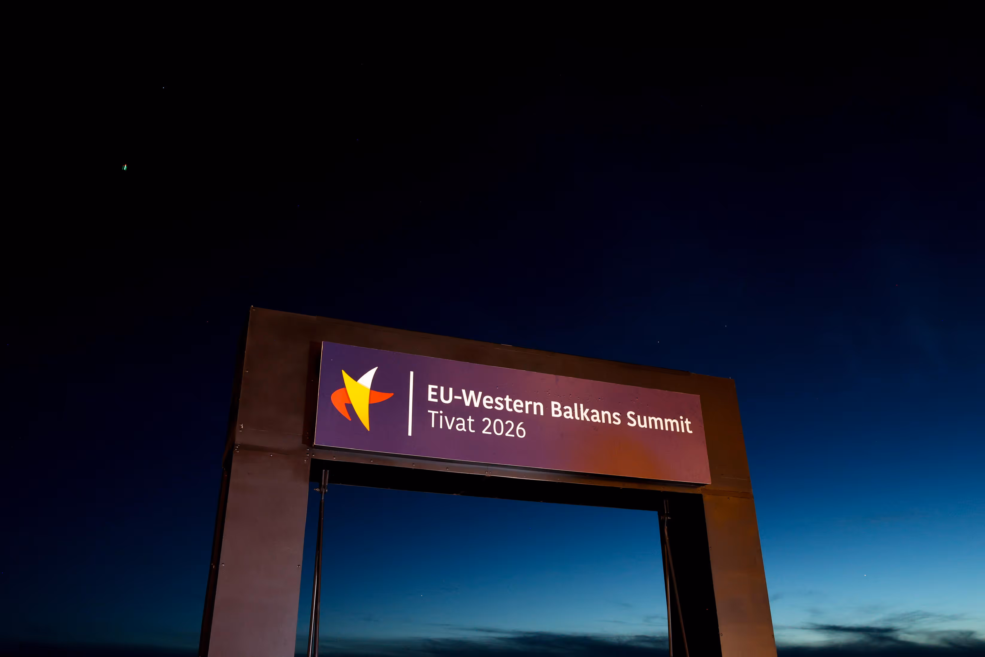EU–Western Balkans Summit Tivat 2026 gateway sign illuminated at night against deep blue sky