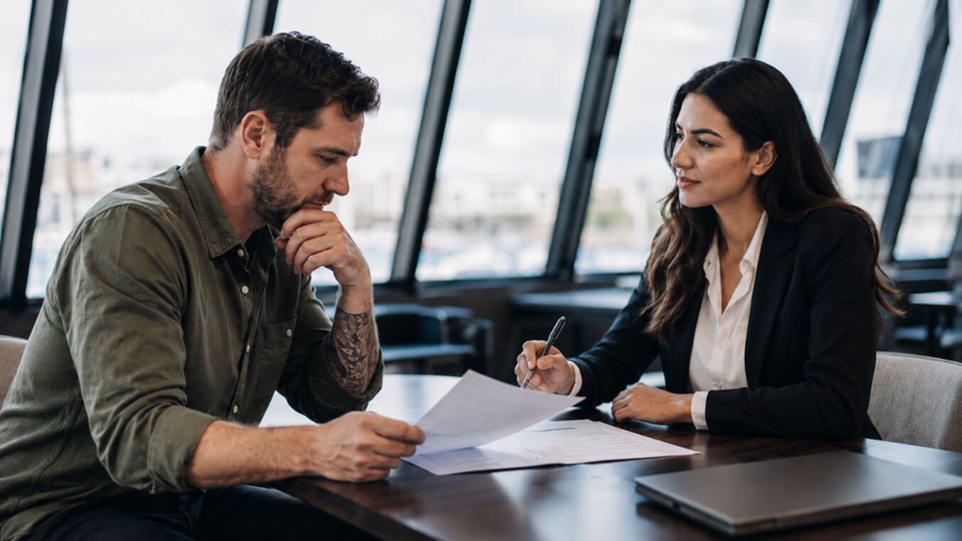 Veteran reviewing DVA bullying claim documents with a supportive consultant in a professional office setting.
