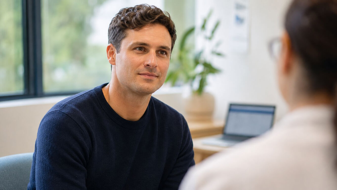 Young Australian veteran discussing a DVA mental health care plan with a provider in a civilian clinic.