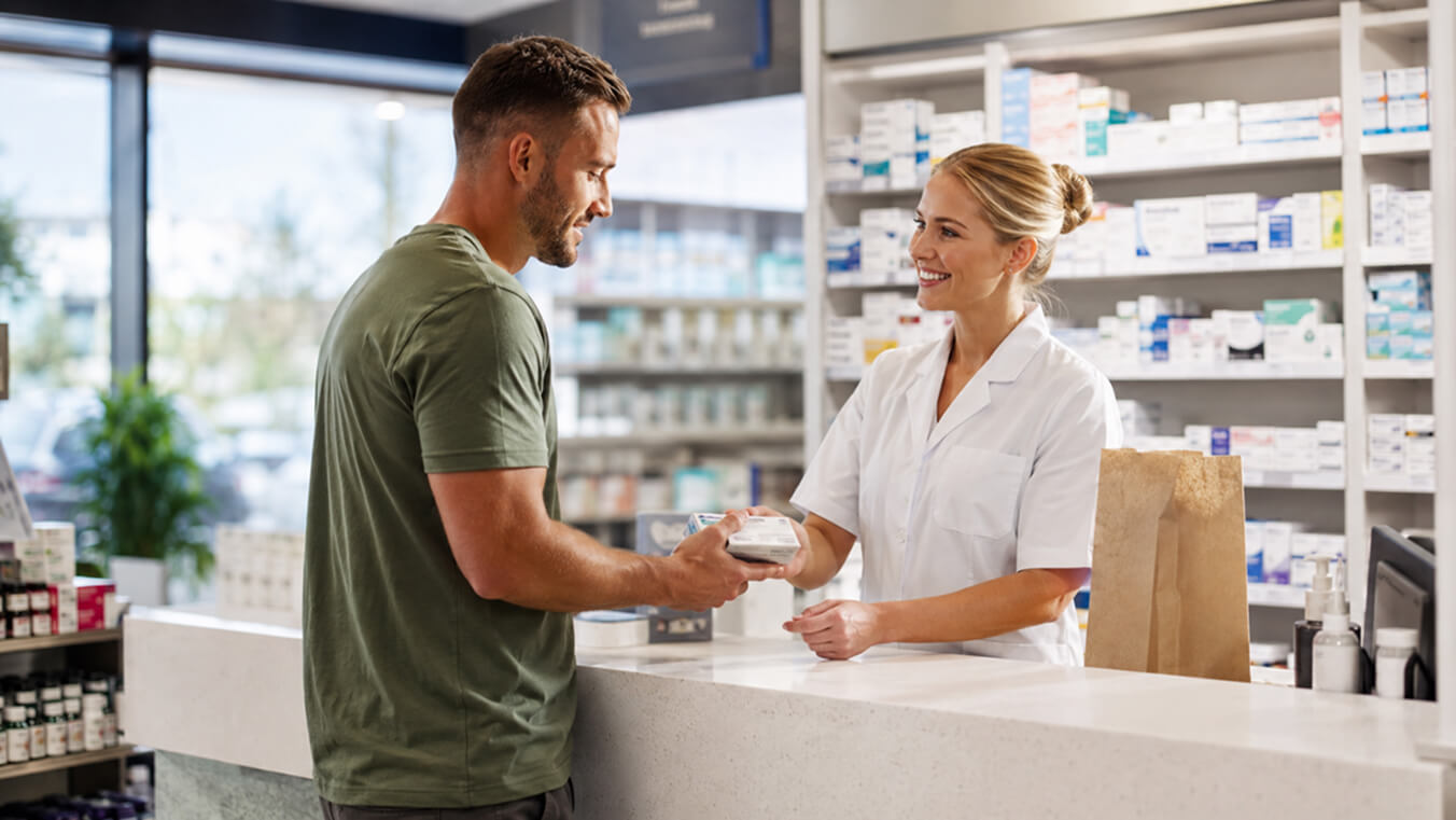 Commonwealth veteran receiving prescription medicine from a pharmacist at an Australian pharmacy through DVA Repatriation Pharmaceutical Benefits Scheme support.