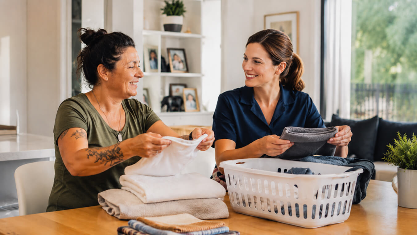 Female veteran and a home care worker folding laundry together under the Veterans Home Care program in an Australian home.