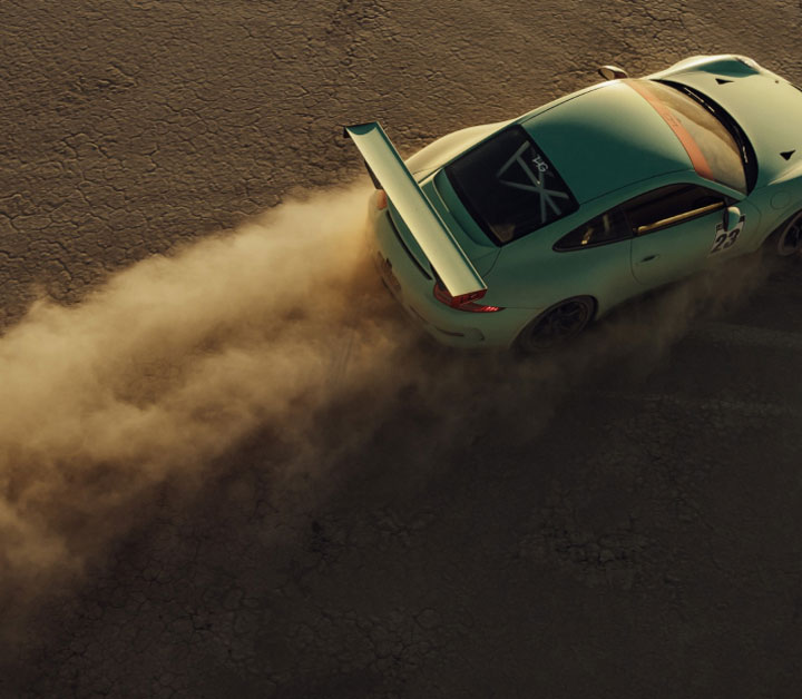 Vehicle driving though open space leaving a cloud of dust behind it