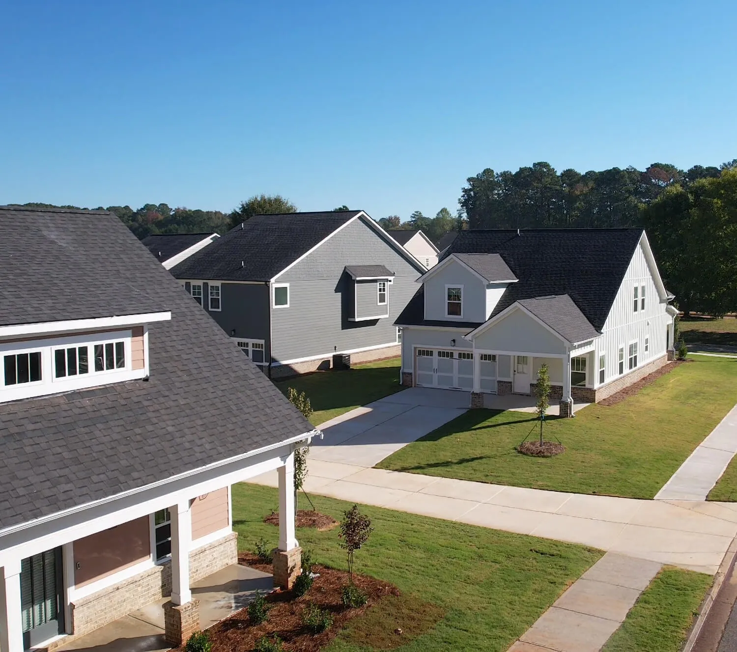 Suburban neighborhood with modern single-family homes, green lawns, and clear blue sky.