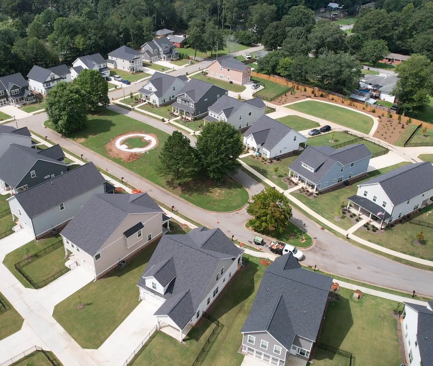 Aerial view of a suburban neighborhood with houses, lawns, trees, and curved streets.