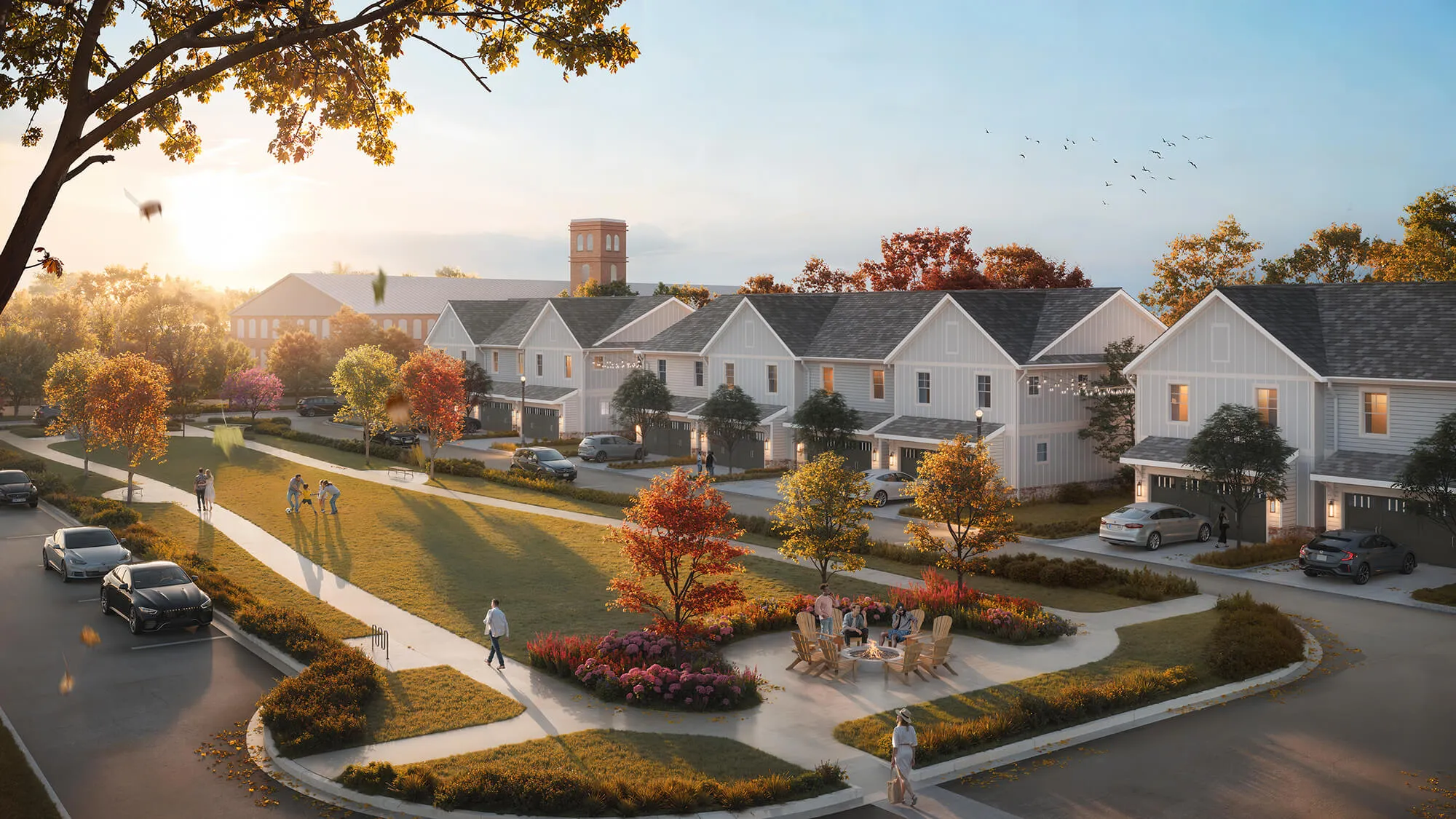 Residential neighborhood with modern townhouses, people playing, walking, and sitting around a fire pit at sunset.