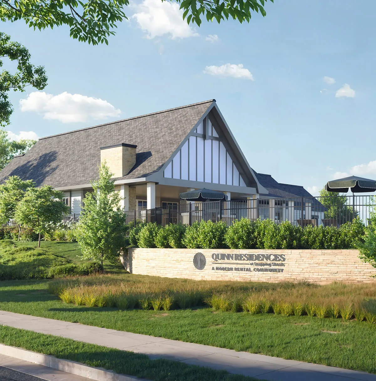 Modern building with steep roof and stone sign reading Quinn Residences surrounded by greenery and blue sky.