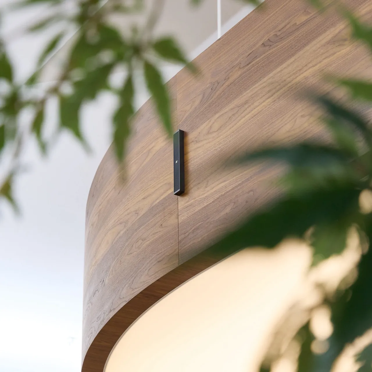 Ronde houten verlichtingsarmatuur aan het plafond met een subtiele speaker in verwerkt.