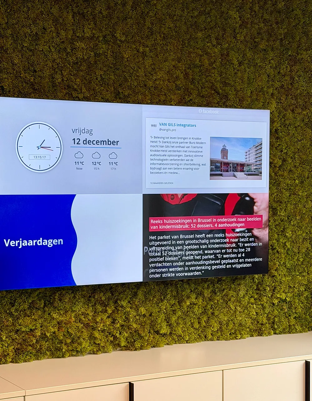 Digitale display met klok, weersvoorspelling, Facebook-bericht van VAN GILS en nieuws.
