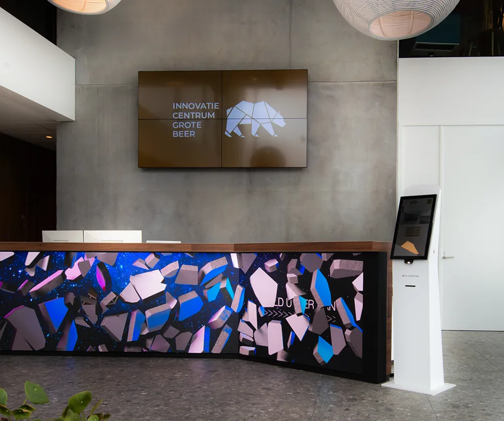 Receptiebalie met kleurrijk abstract patroon en een kiosk voor bezoekersregistratie.