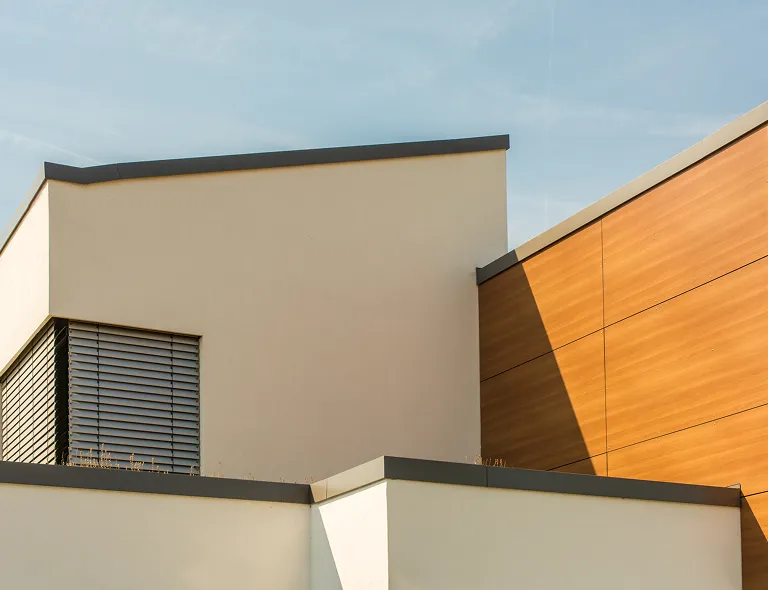 Moderner Gebäudeteil mit weißen und holzfarbenen Fassaden unter klarem Himmel.