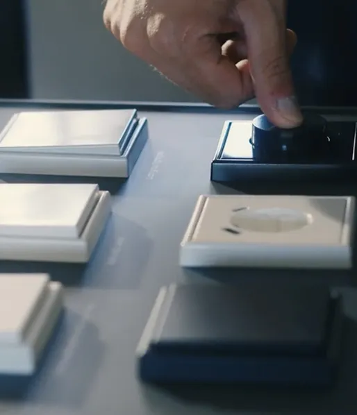 Hand dreht schwarzen Drehknopf auf einer modernen Steuerung mit weißen quadratischen Tasten.