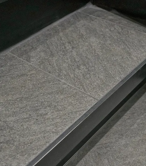 Nahaufnahme von grauen, rechteckigen Bodenfliesen mit glatten Fugen.