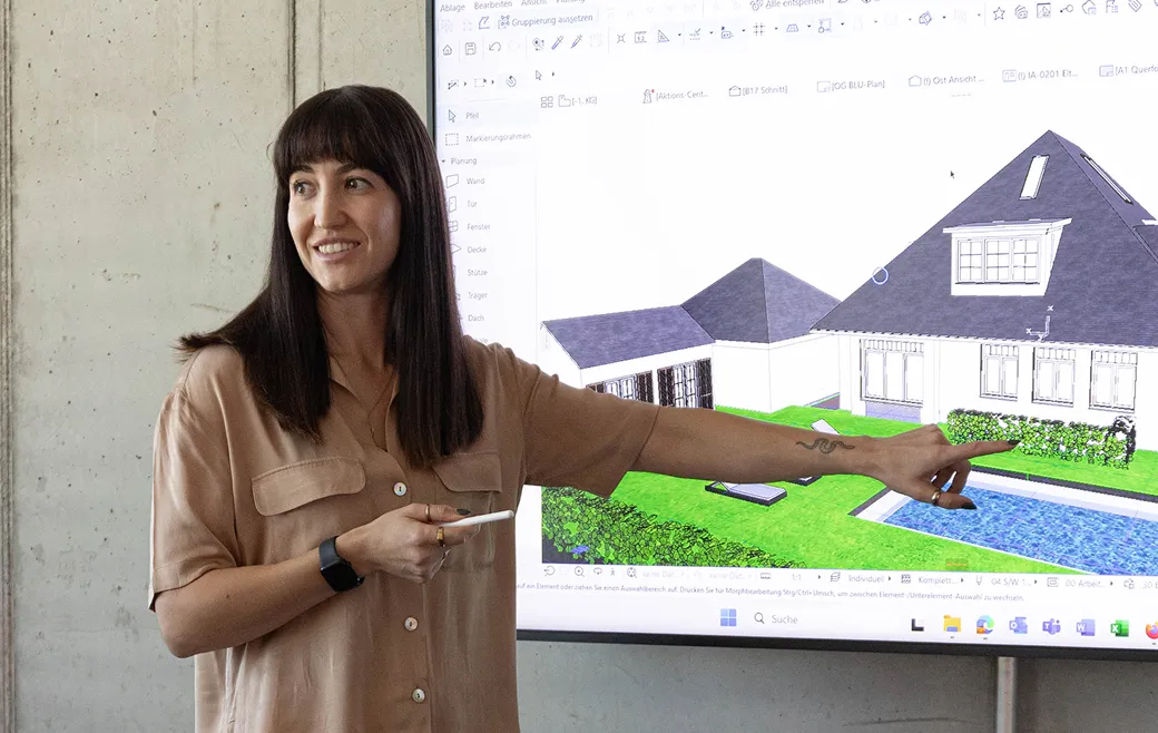 Frau zeigt auf einem Bildschirm ein 3D-Modell eines Hauses mit Garten und Pool.
