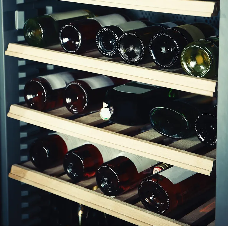 Mehrere Weinflaschen liegen horizontal auf Holzregalen in einem Weinkühlschrank.