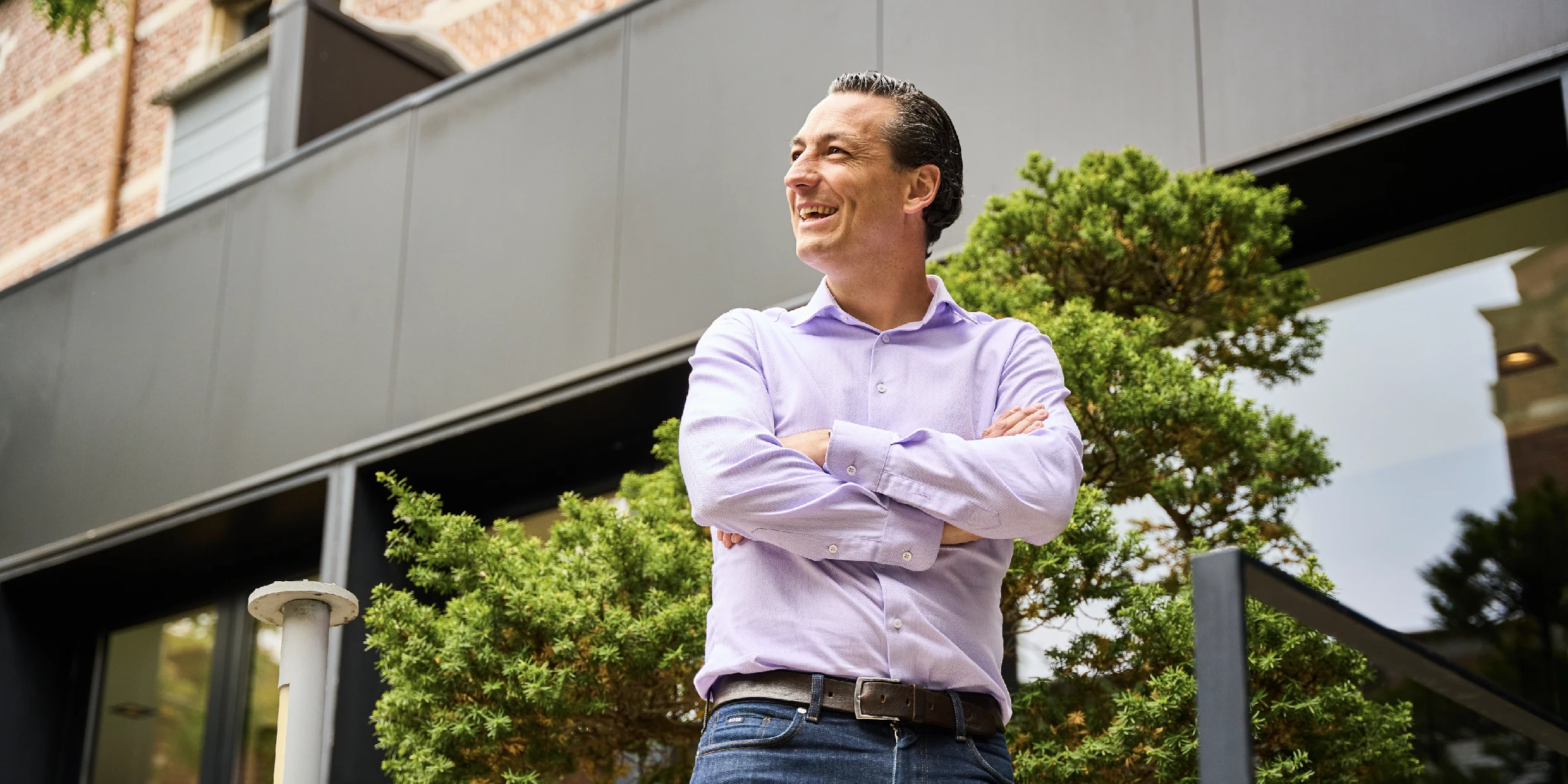 Posed photo of one of our slients while standing outside smiling with crossed arms.