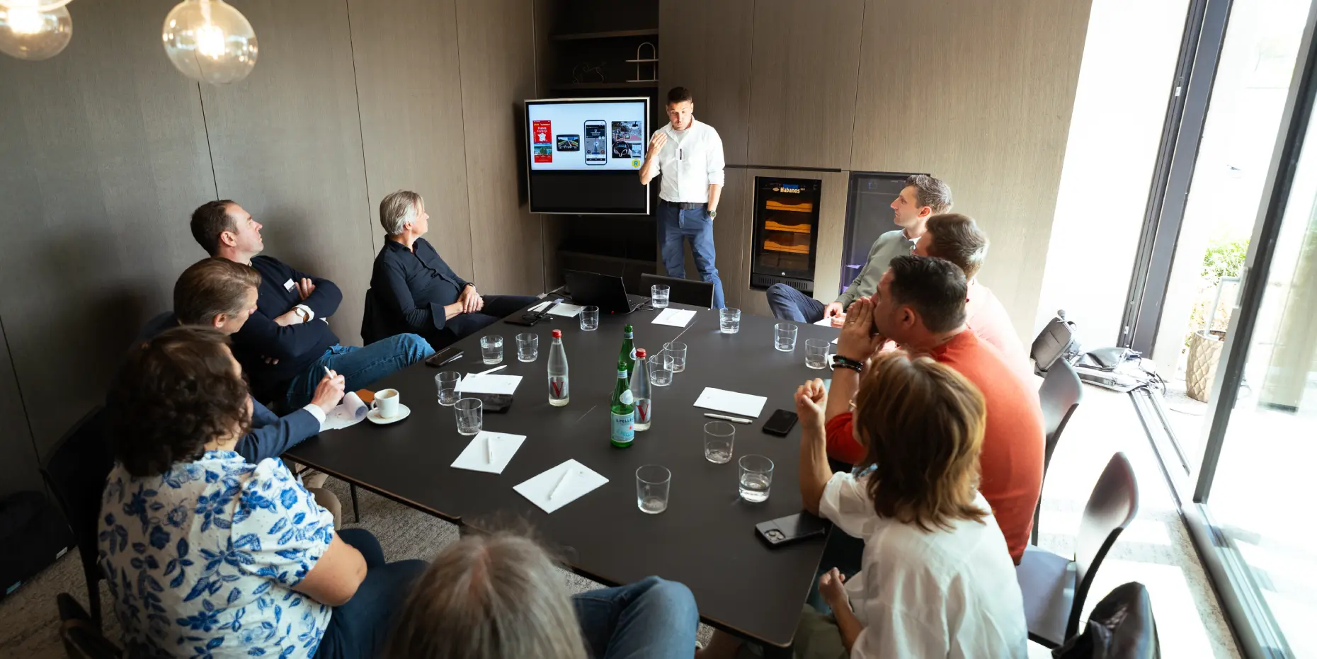 Photo taken by Unmute You during a meeting inside a conference room with some people sitting down and presenting up front.