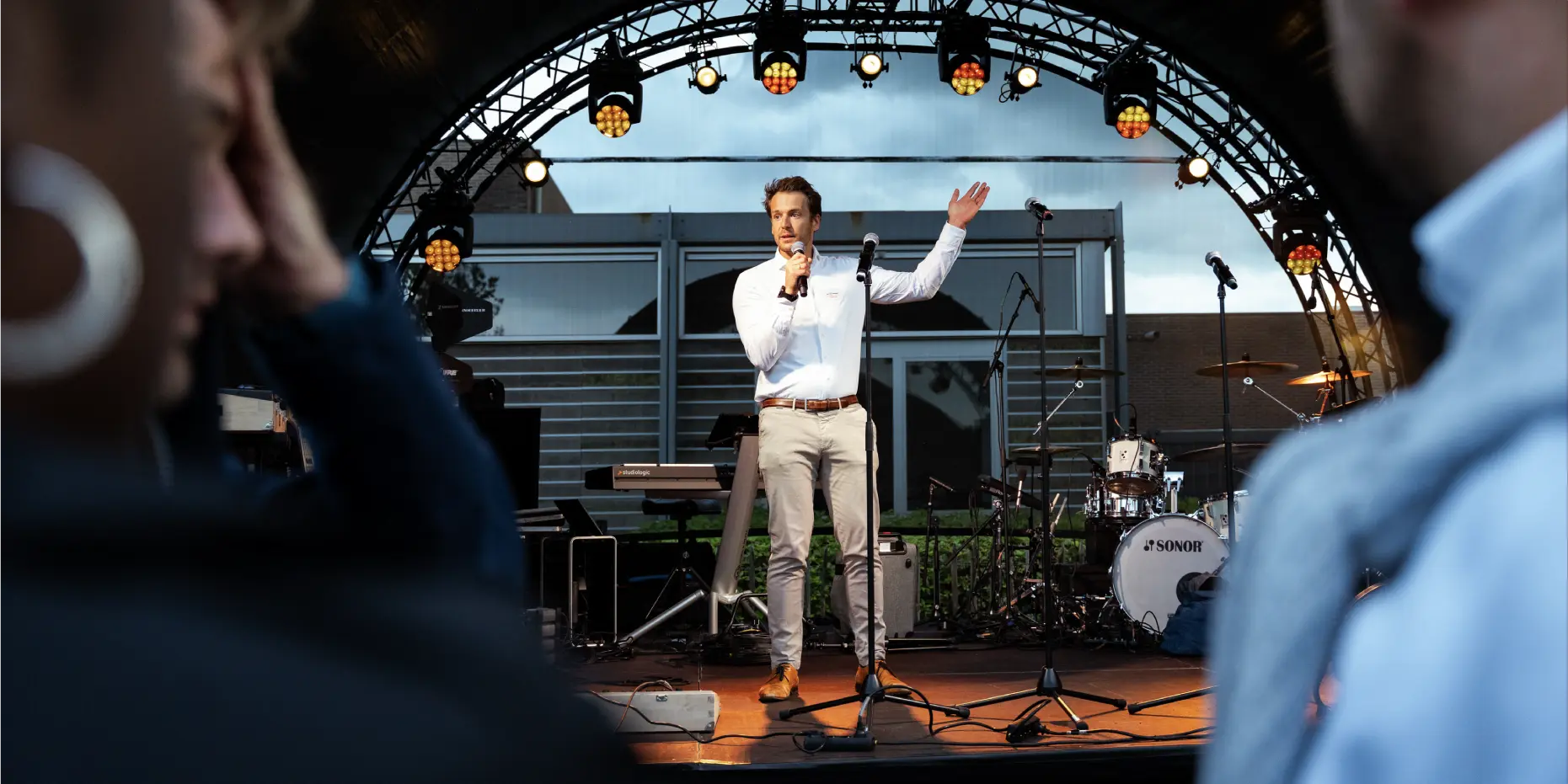 Photo taken by Unmute You during an event where one person is standing up on a stage with a microphone.