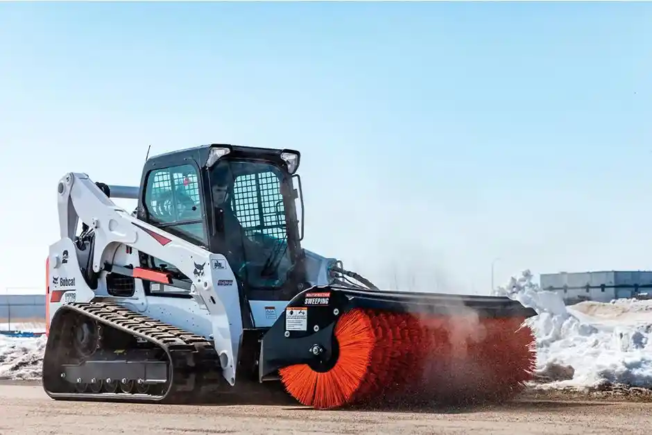 Parking lot sweepers near me cleaning an industrial warehouse floor using a skid steer