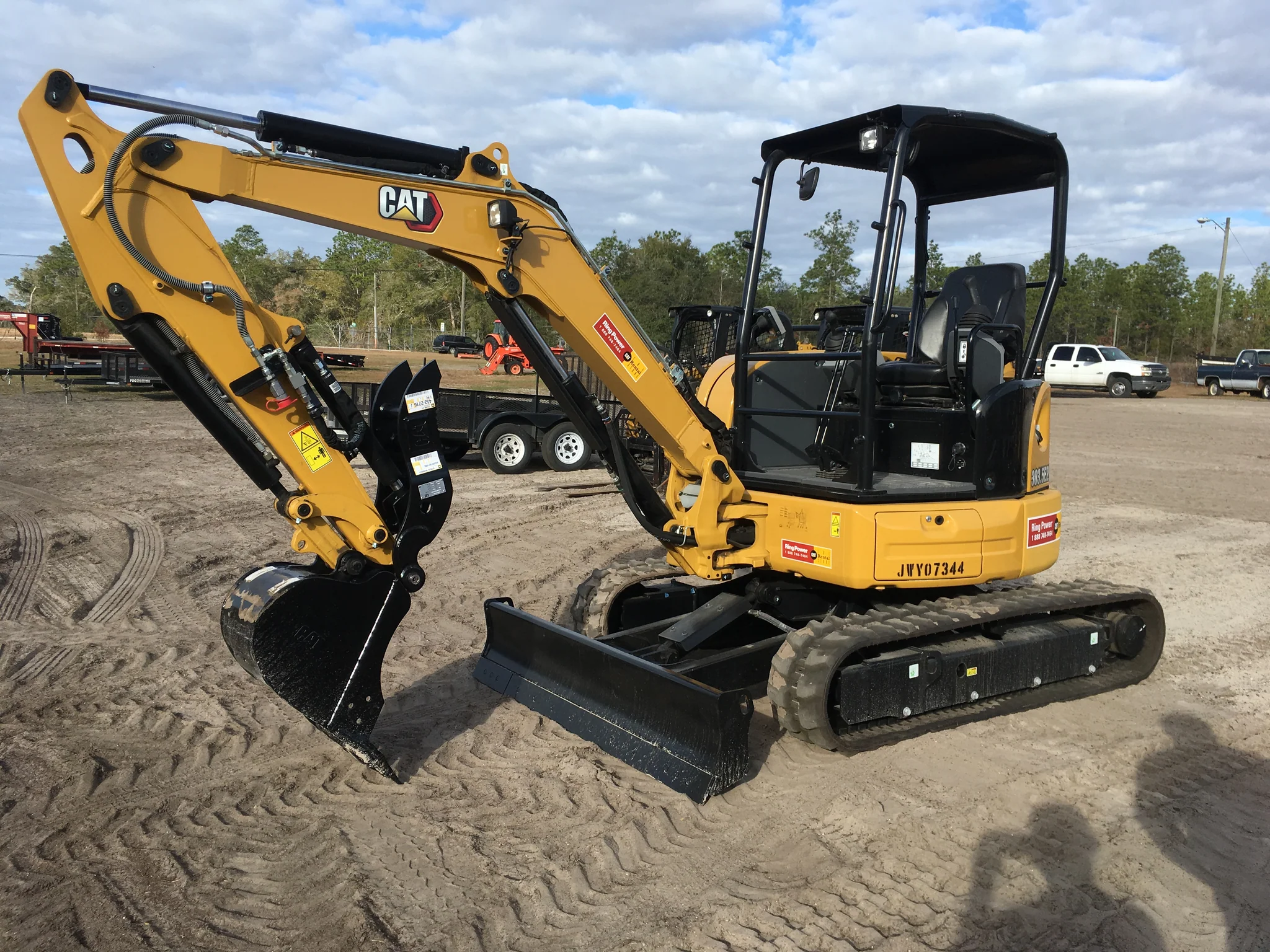 Small excavator hire with rubber tracks parked safely on an interlock driveway