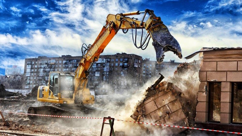 Mini digger hire with mechanical thumb attachment moving heavy rocks