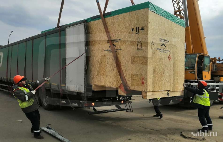 A busy, narrow construction site where a telescopic handler rental unit is lifting materials directly from a delivery truck to the upper floors, bypassing ground storage.