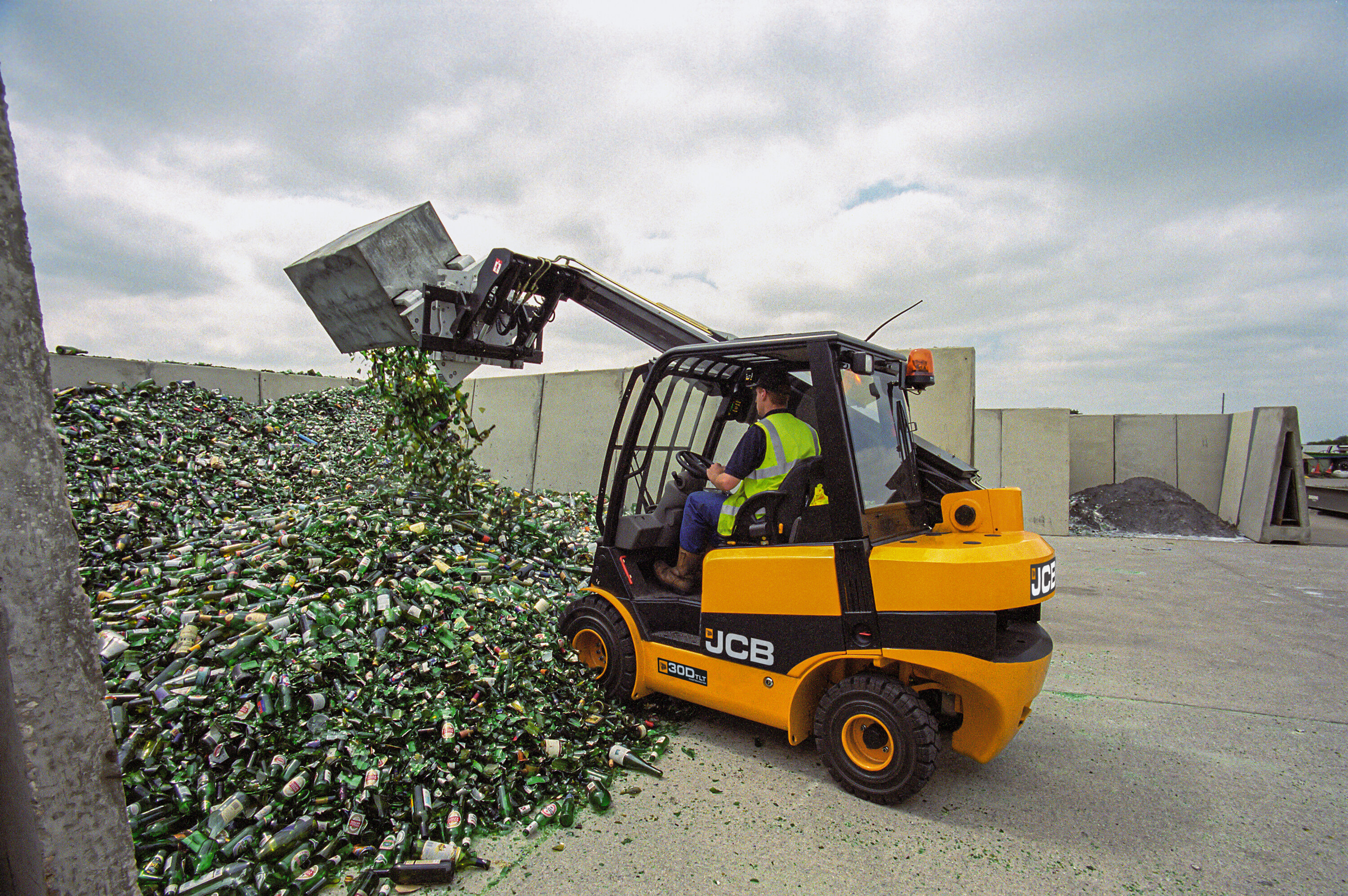A telehandler extending its boom over a garden boundary wall to perform lifting construction materials into a backyard swimming pool excavation site.