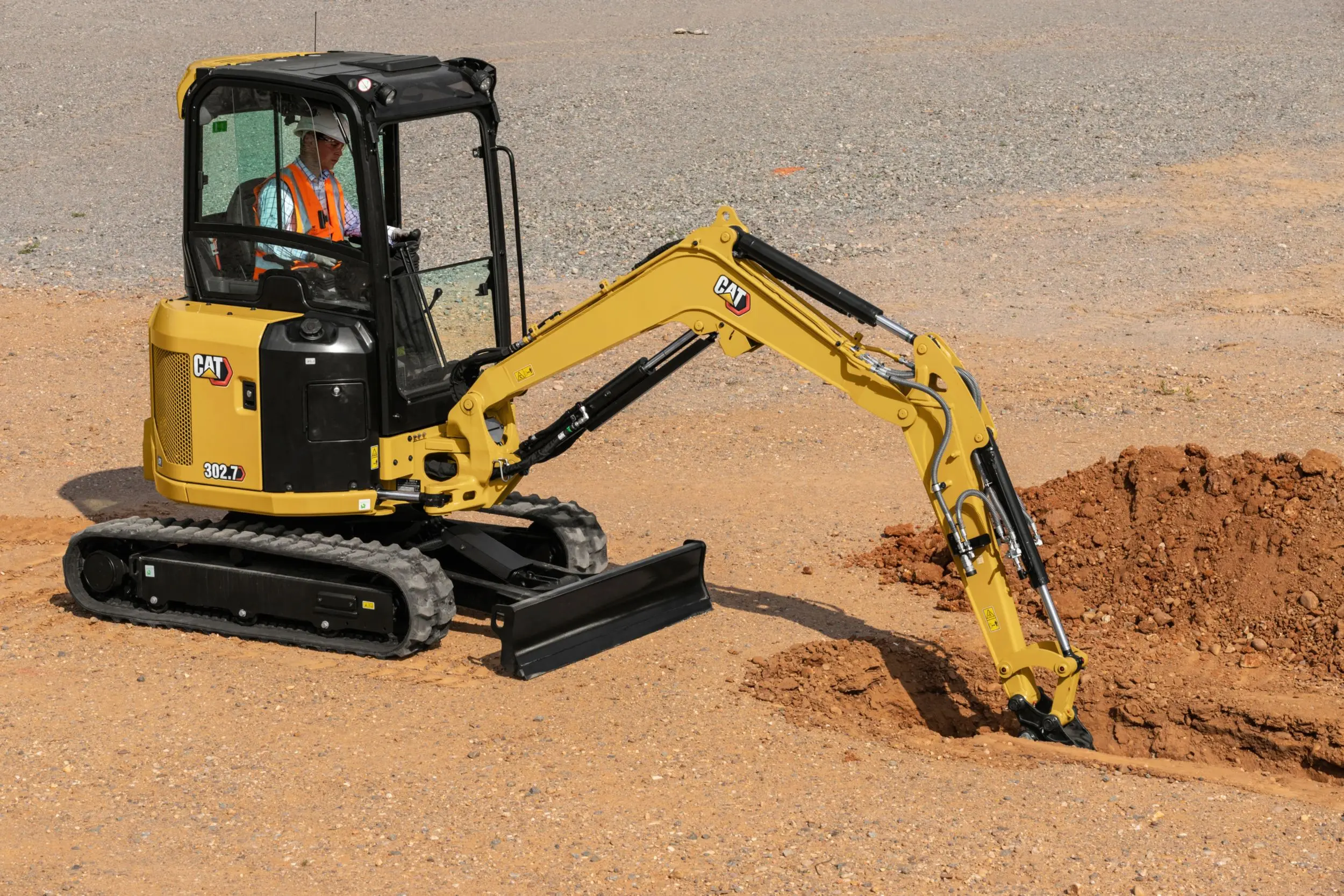 An electric mini excavator rental unit working indoors, highlighted by a lack of exhaust fumes and a power cable, ensuring safety in confined spaces.