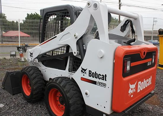 A mini bobcat hire unit (MT series) working in a narrow residential side alley, removing garden waste without damaging the walls