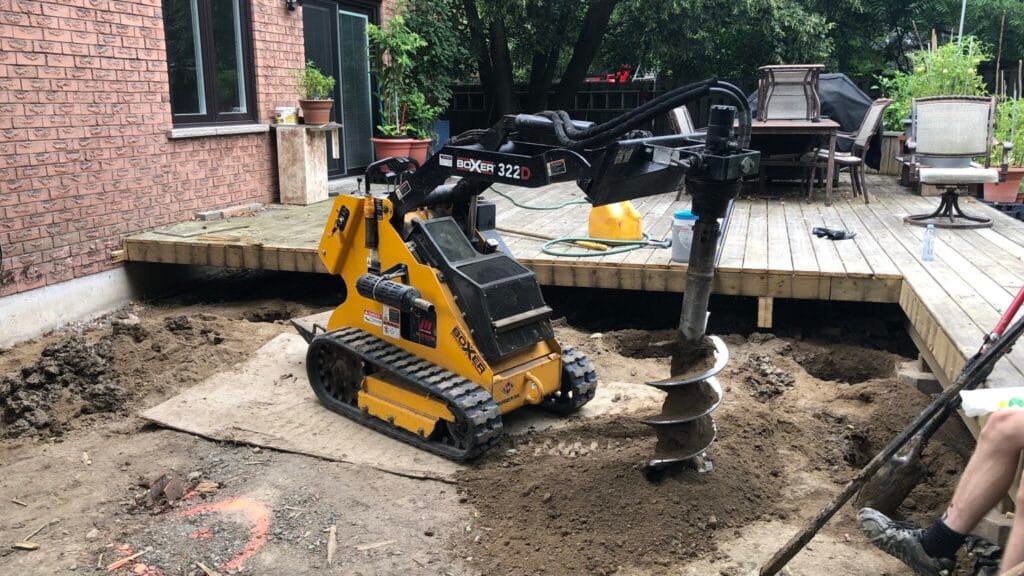 A Bobcat with auger rental unit drilling a wide-diameter hole for a date palm tree in a Dubai landscape project.