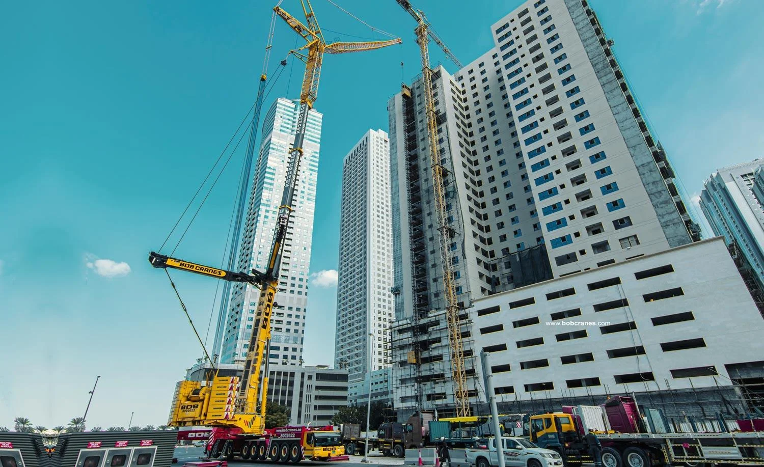 A large All-Terrain crane deployed for heavy lifting equipment rental, placing a massive chiller on a commercial roof.