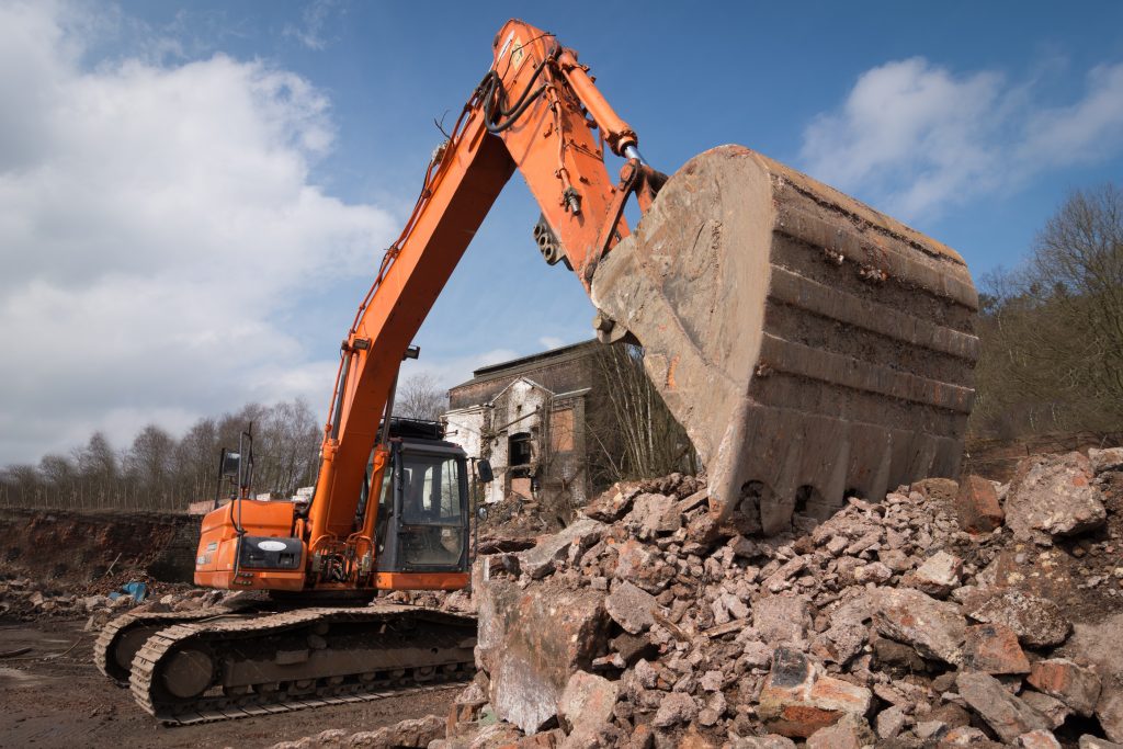 A bulldozer pushing a large pile of desert scrub and debris during land clearing operations on a Dubai construction site.