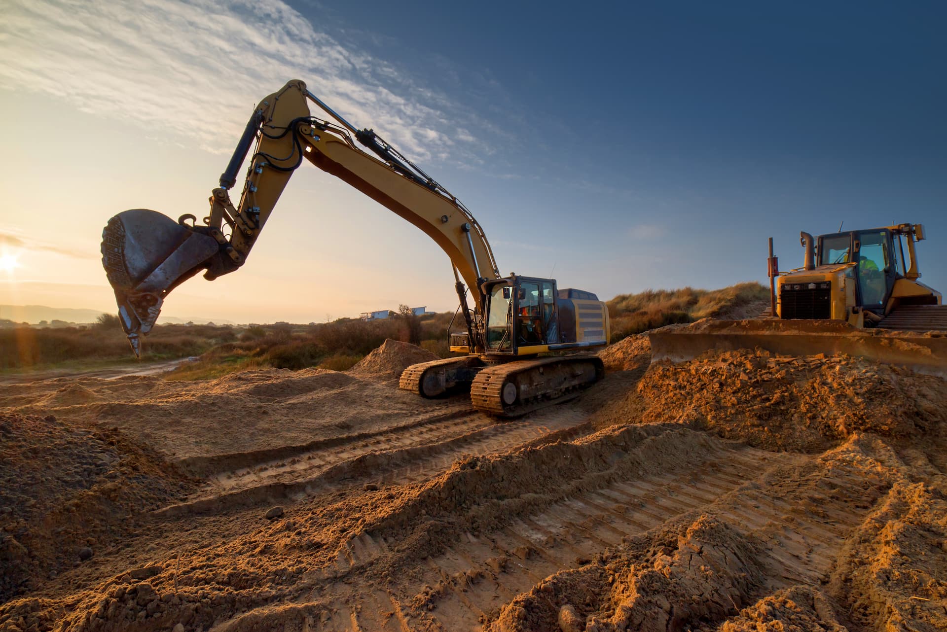 An excavator loading mixed construction waste and rubble into a dump truck, illustrating professional plot cleaning services.