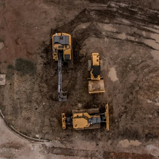 A wide-angle shot of a massive commercial land clearing services project with multiple machines working in tandem to prepare the ground.