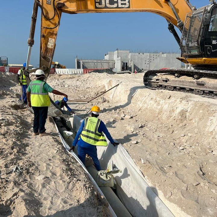 A JCB 3CX hire machine driving along a Dubai road, demonstrating its mobility and road-legal status.