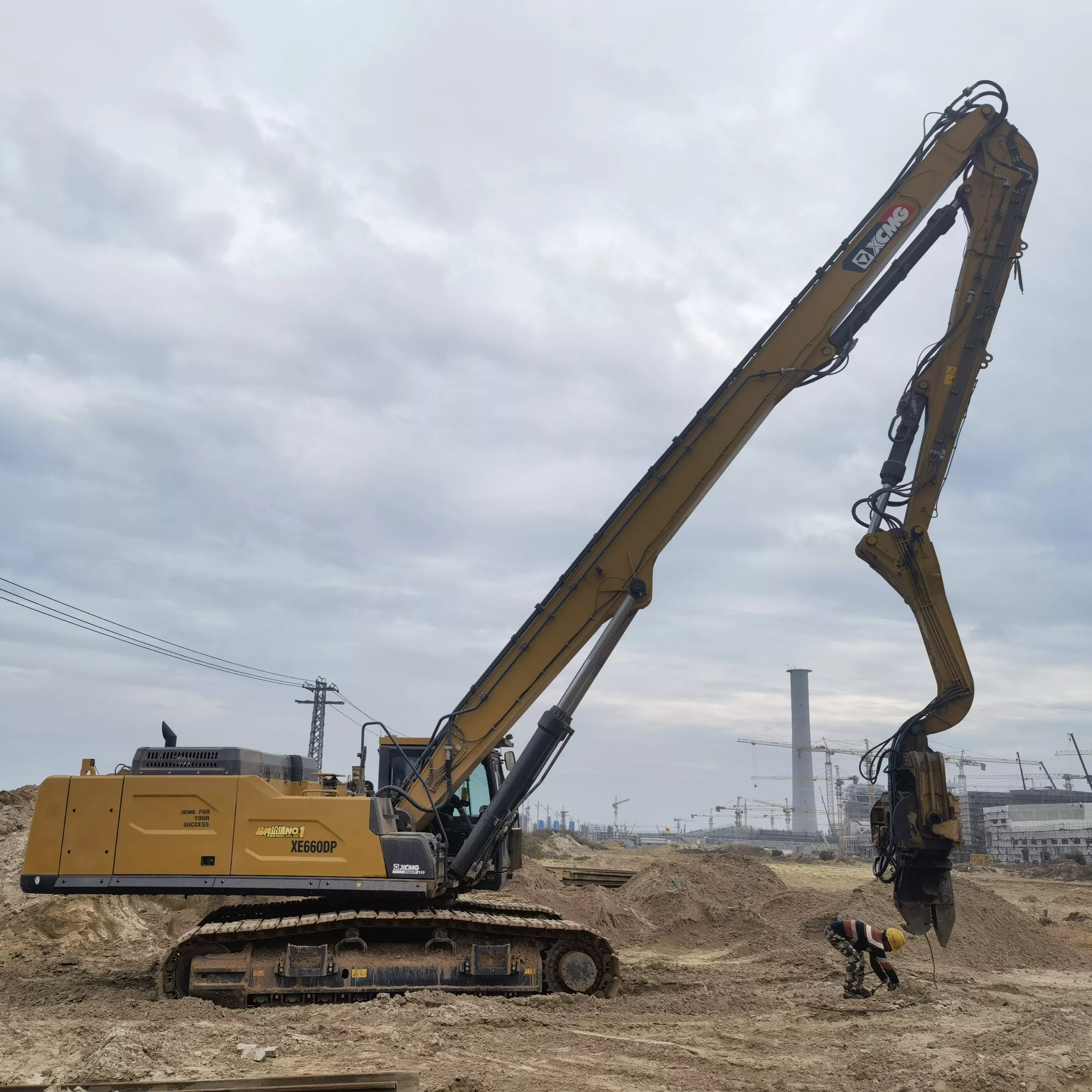 A 30-ton excavator equipped with a side-grip vibro hammer driving a 9-meter steel sheet pile into the ground on a Dubai construction site.