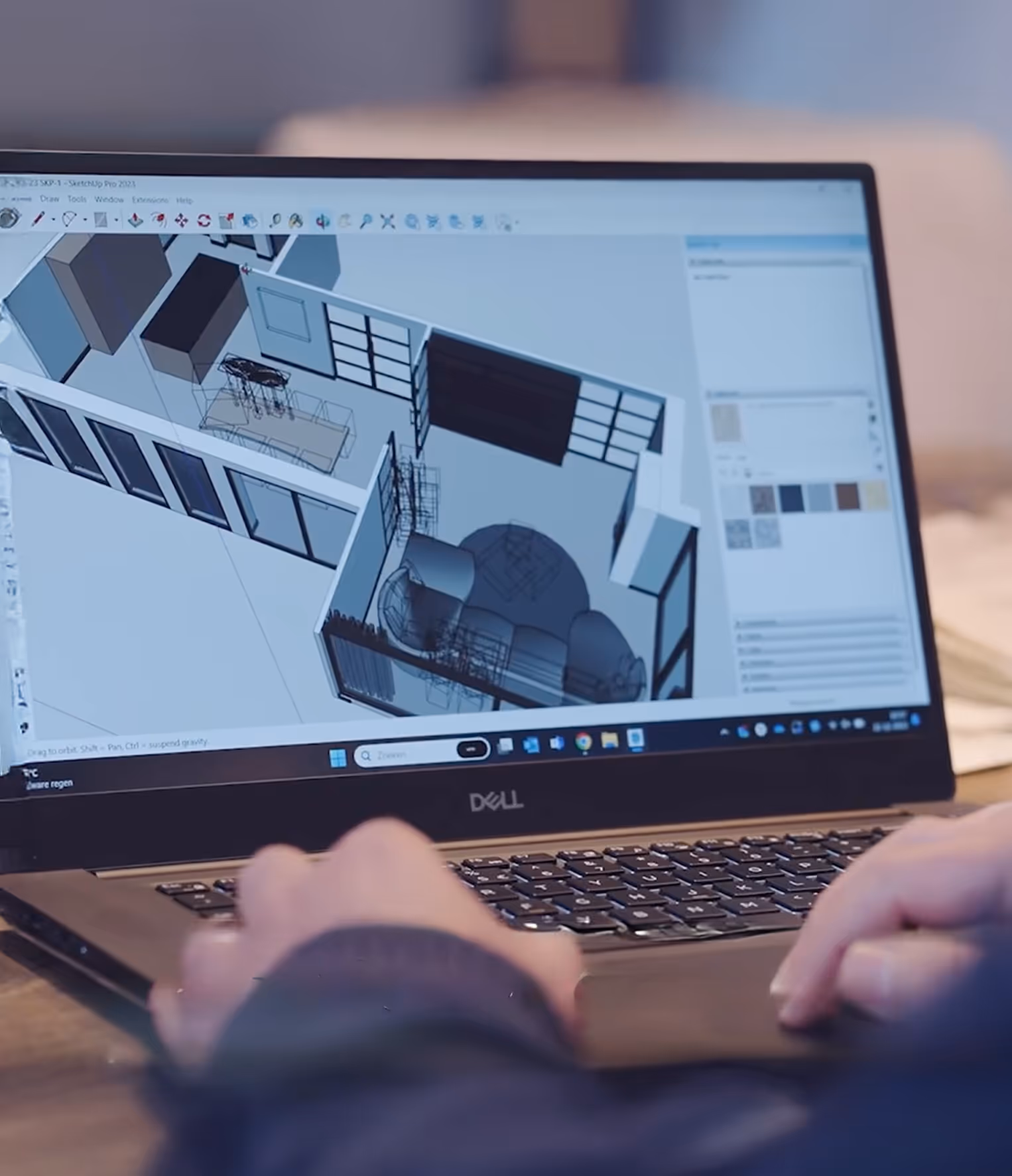 Handen bedienen een Dell laptop met een 3D-model van een kamerindeling op het scherm.