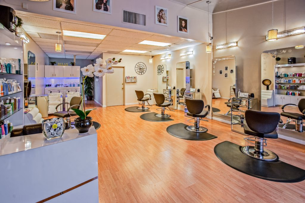 The interior of a hair salon has chairs ready for clients and shelves stocked with hair products.